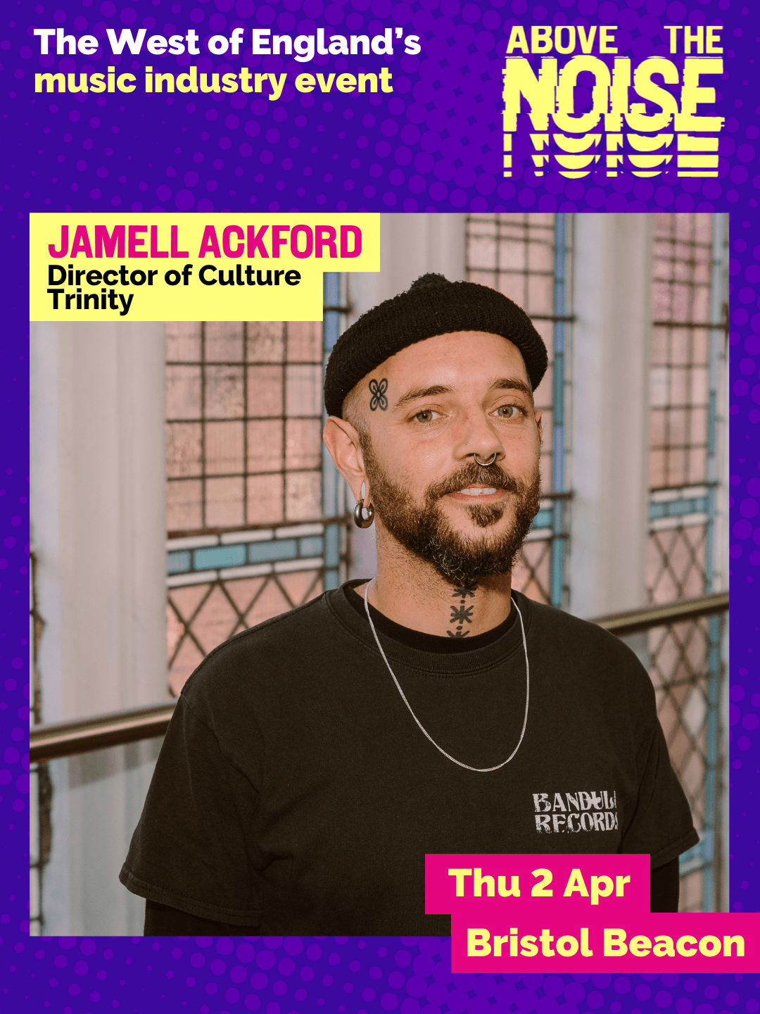 Jamell Ackford - Director of Culture Trinity. Thu 2 Apr, Bristol Beacon. A man with a beard wearing a black had and t-shirt stands in front of a stain glass window.