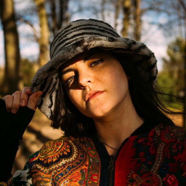 A person wearing a large fake fur had in the woods