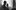 A black and white film image of three people standing in front of a window, looking at something out of shot.