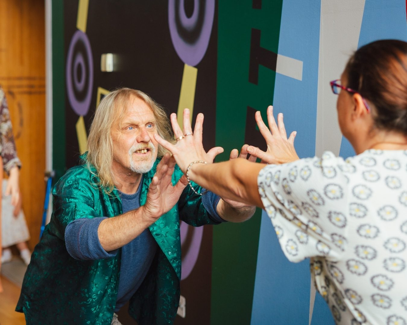 Two performers lean with their hands reaching together in an expressive movement performance
