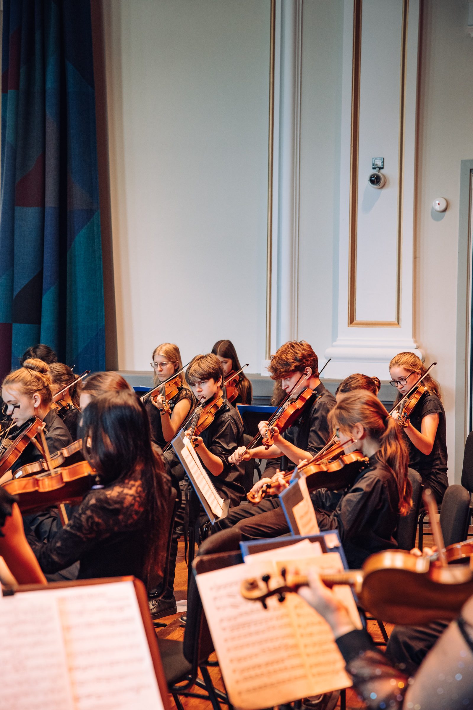 A string orchestra of young people perform, wearing black