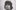 A stylistically blurry image of person with dark shaggy hair looking into the camera awith a ornately decorated while ceiling behind them.