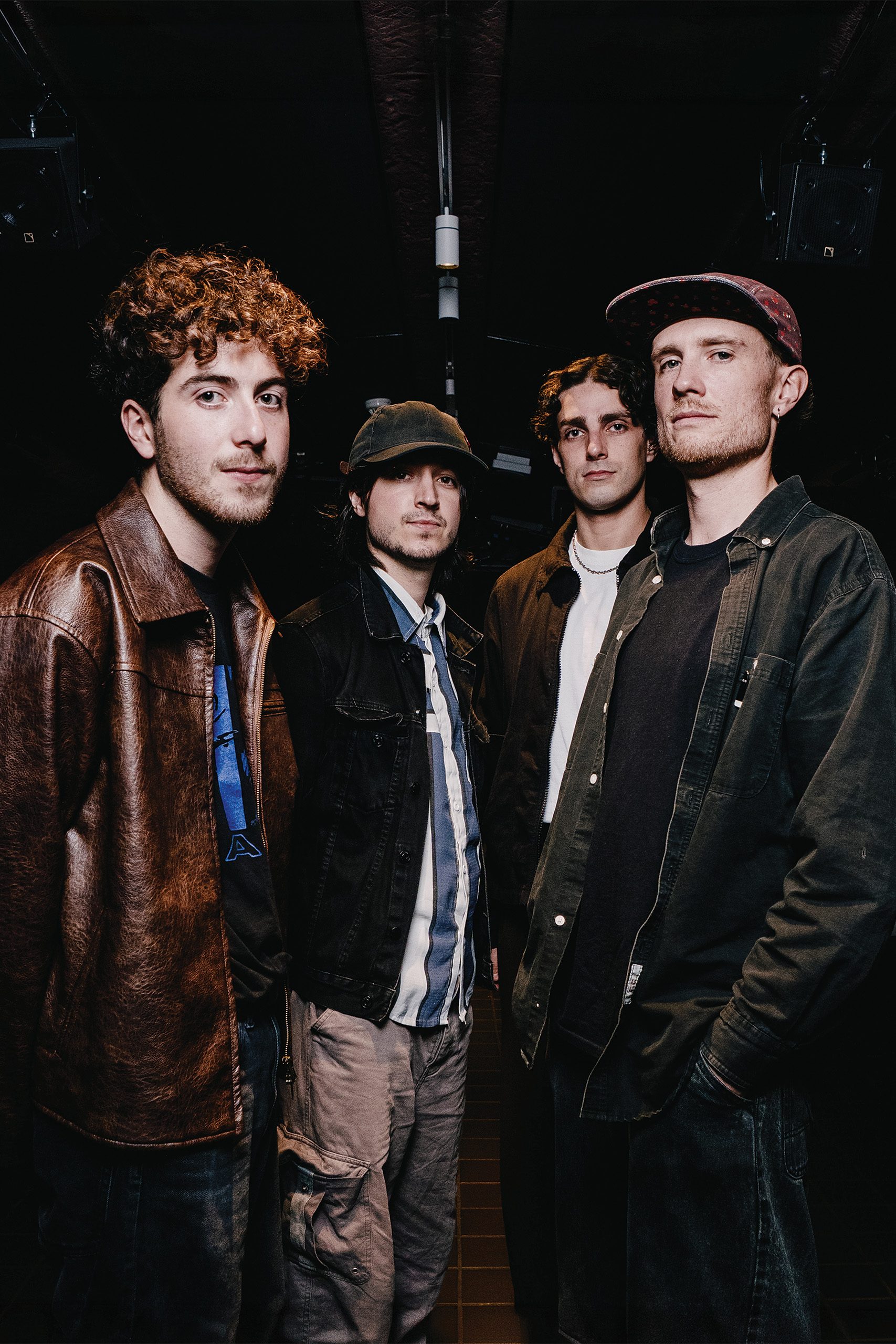 Four people pose together in a dimly lit basement with a brick wall.